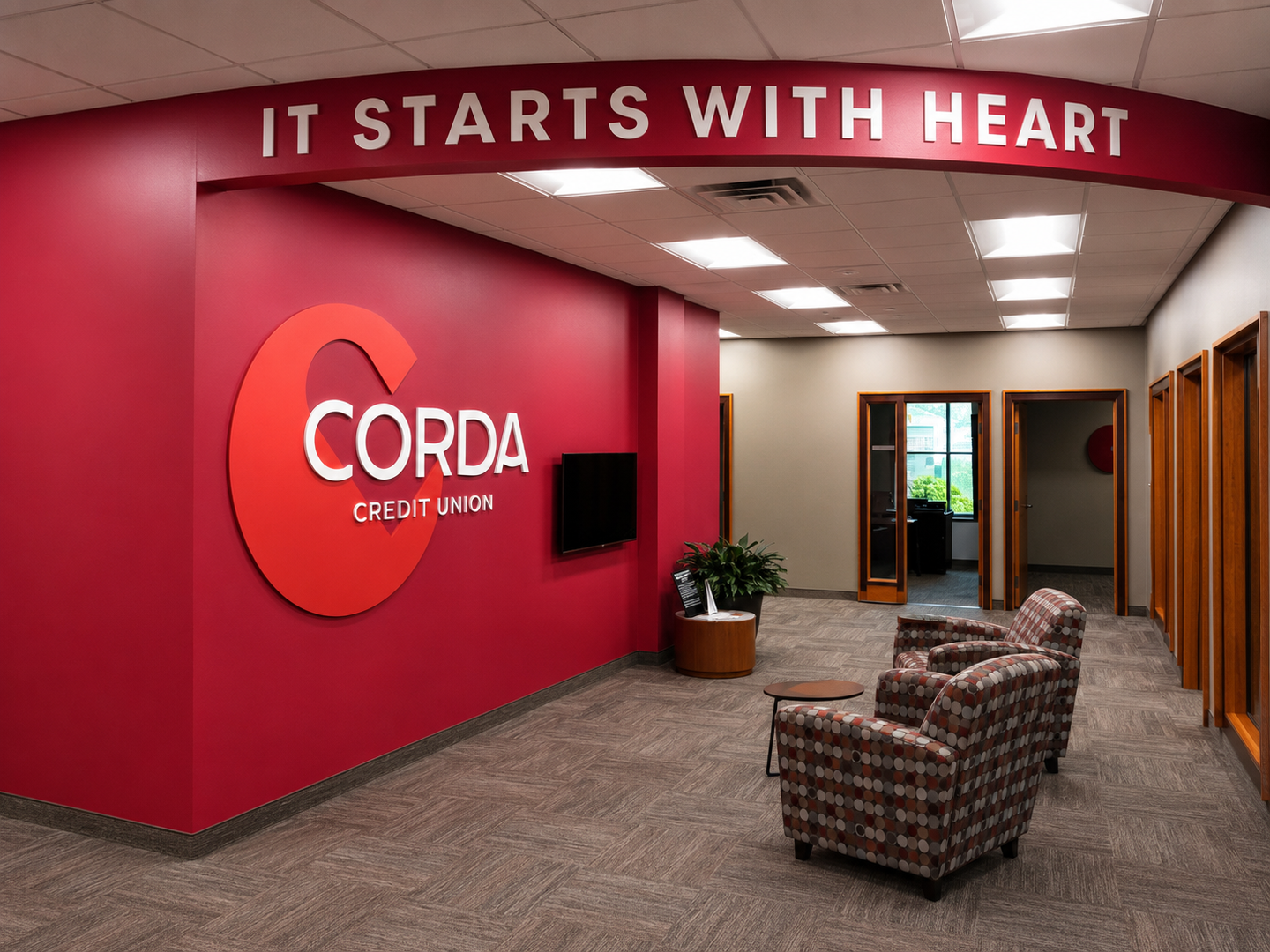 Corporate office lobby with red Corda branding, hallway, and patterned chairs under “IT STARTS WITH HEART” sign