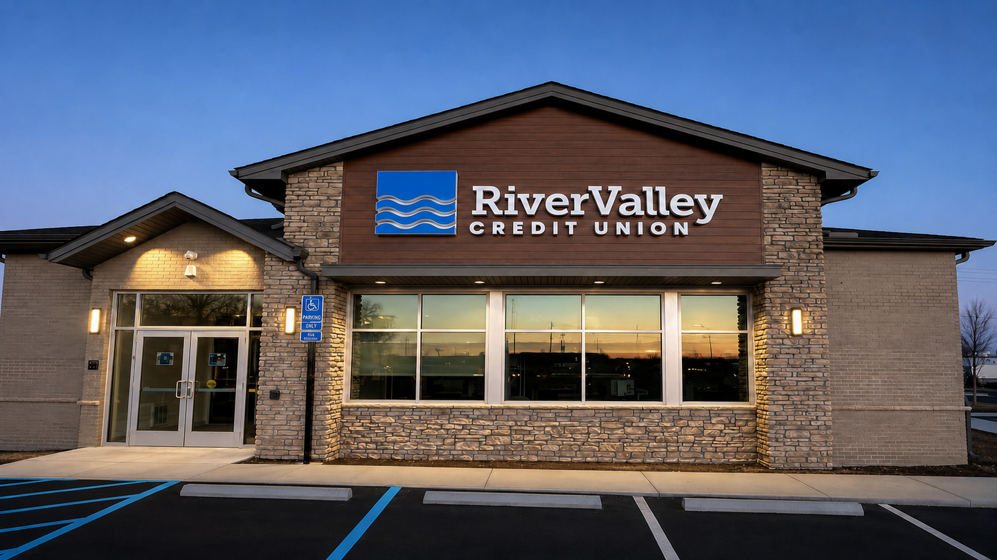 River Valley Credit Union storefront with stone facade and blue-trimmed windows at dusk