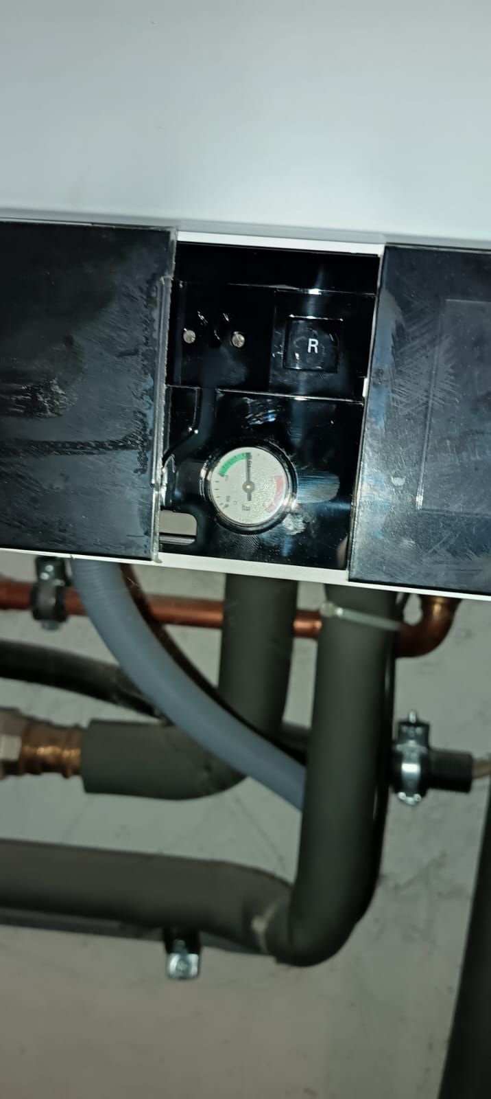 A close up of a water heater with copper pipes coming out of it.