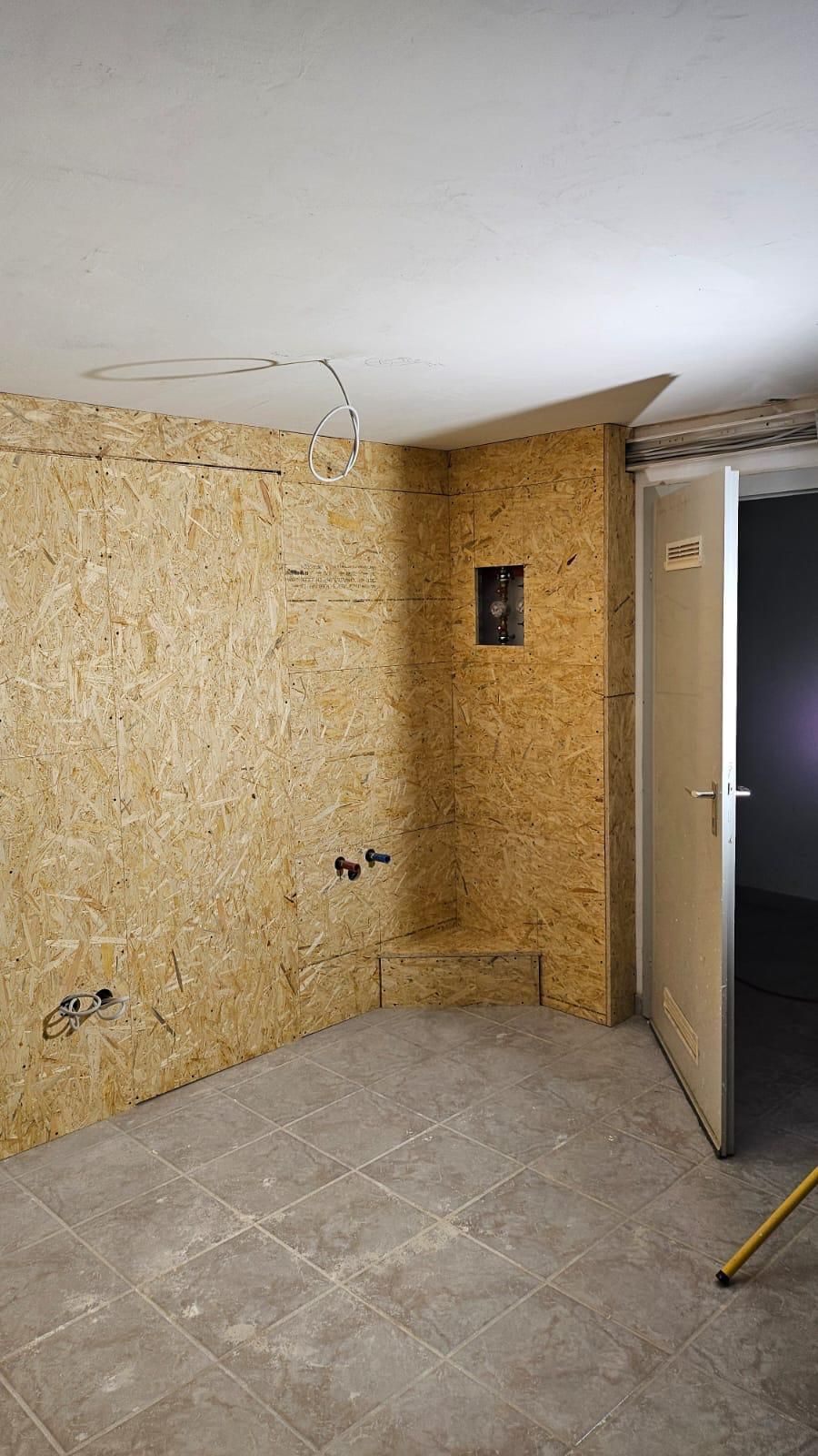 An empty room with a door and a wooden wall.