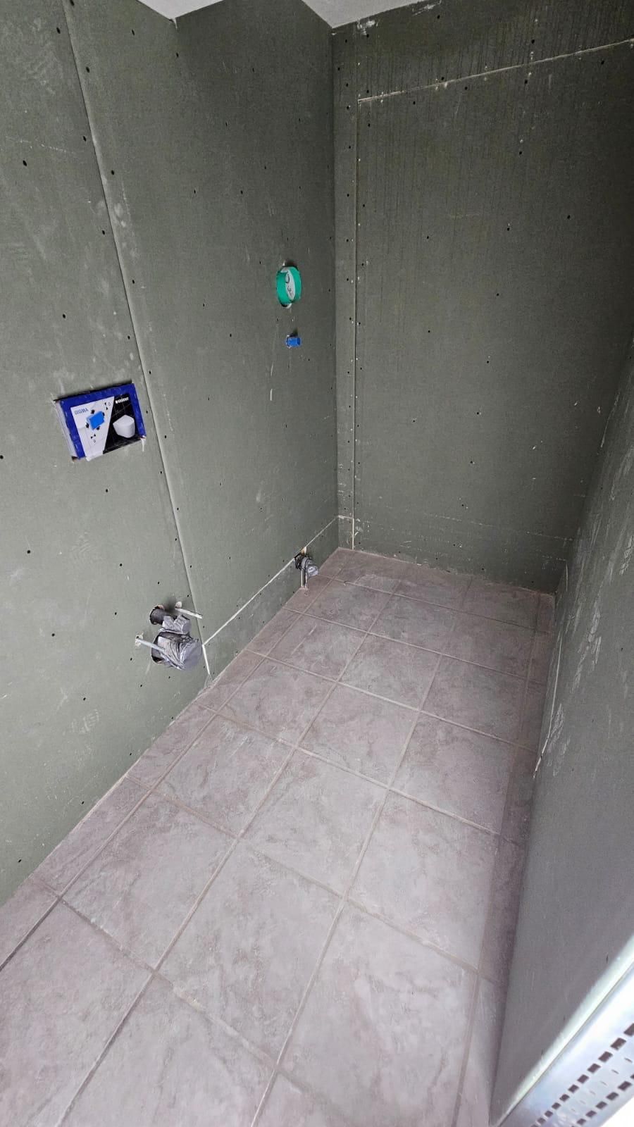 A bathroom under construction with tile floors and walls.