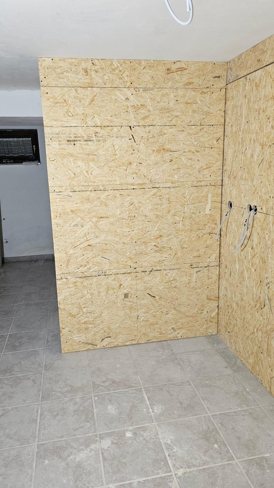 An empty room with a wooden wall and tile floor.