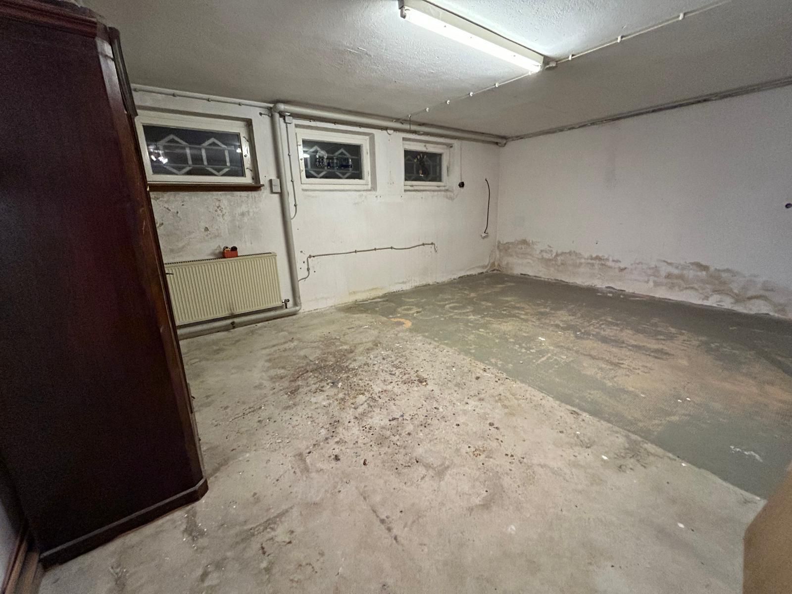 A room with a concrete floor and a wooden cabinet in it.