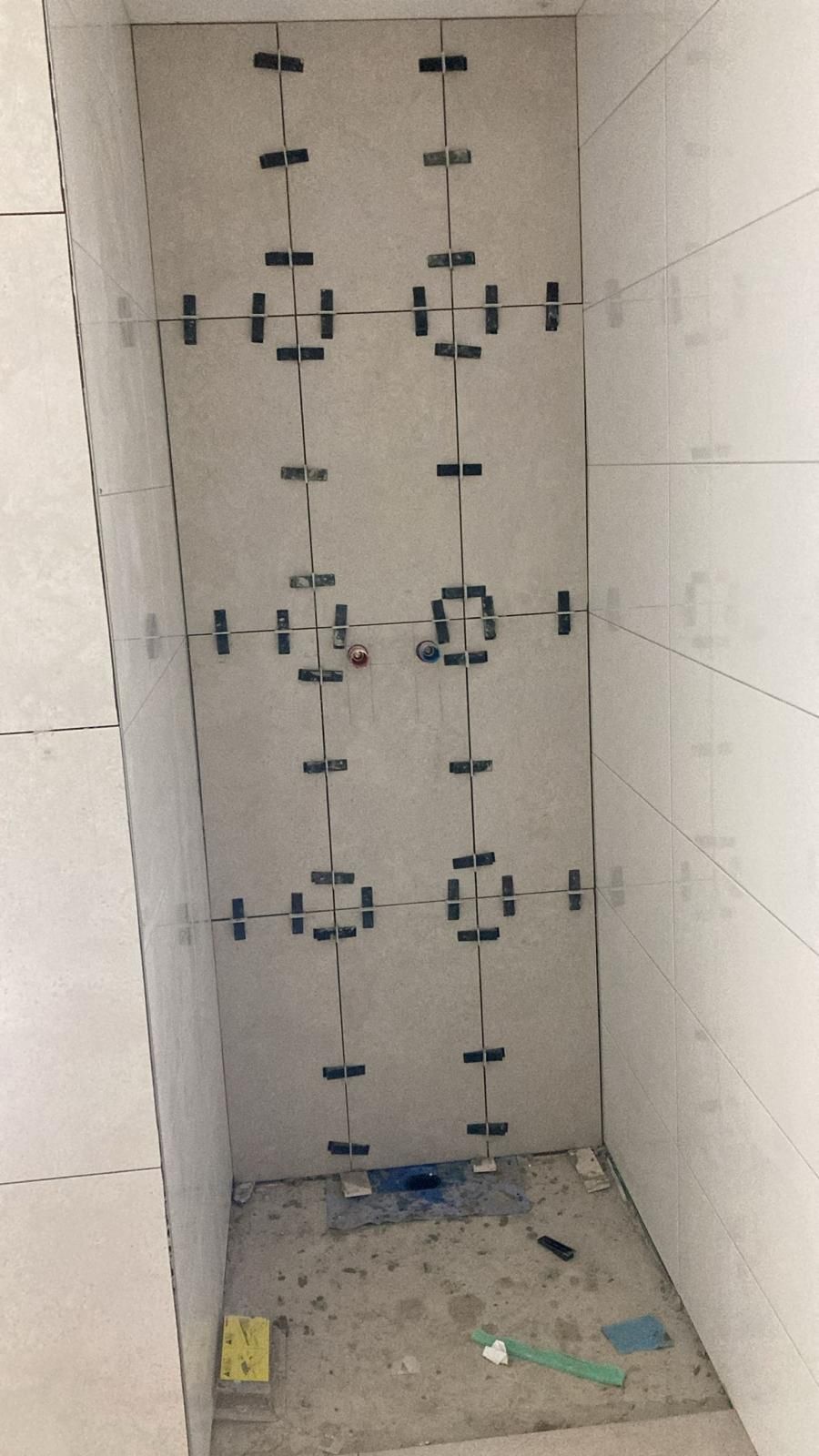 A bathroom under construction with tiles being installed on the wall.