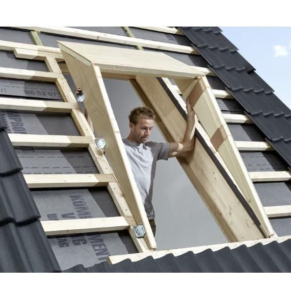 A man is standing in a window frame on a roof