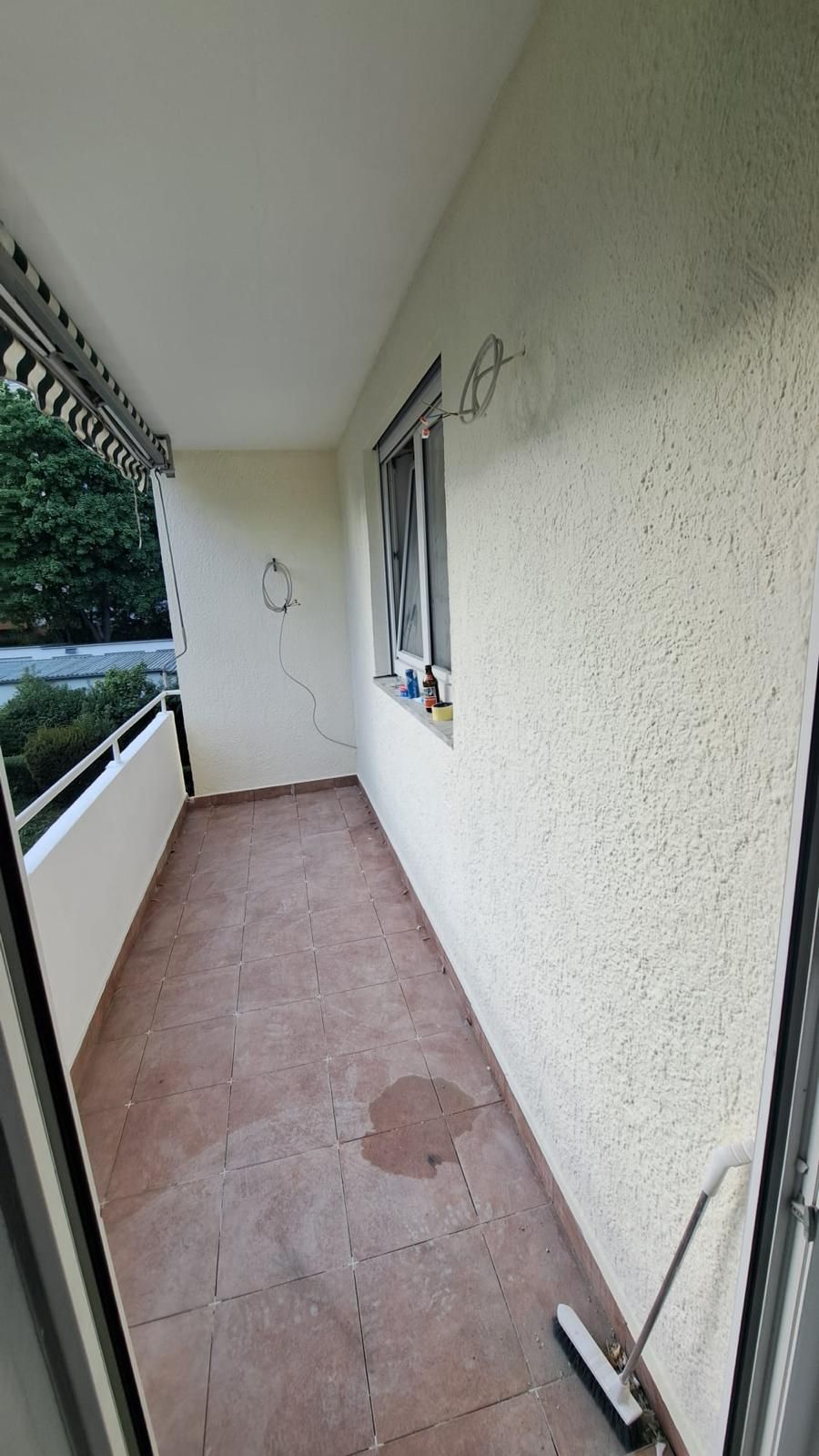 An empty balcony with a window and a broom.