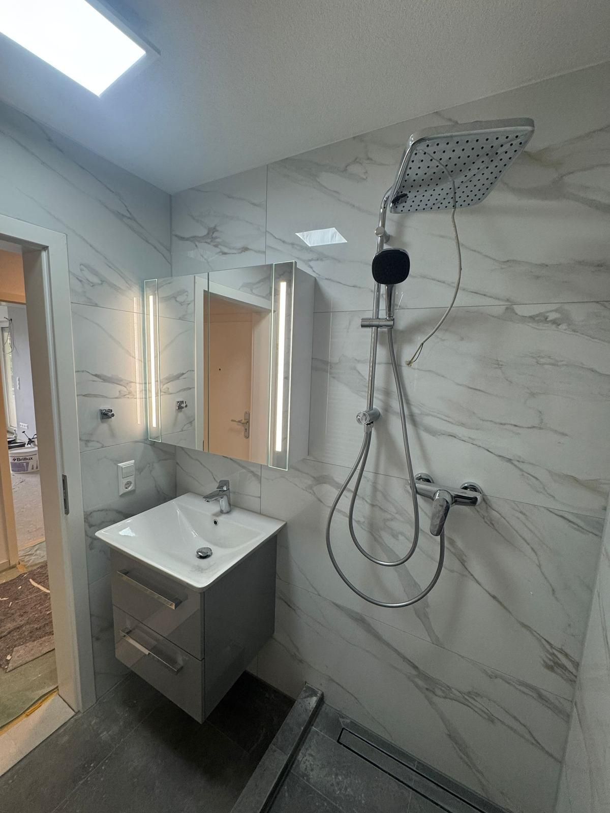 A bathroom with a sink , mirror and shower head.