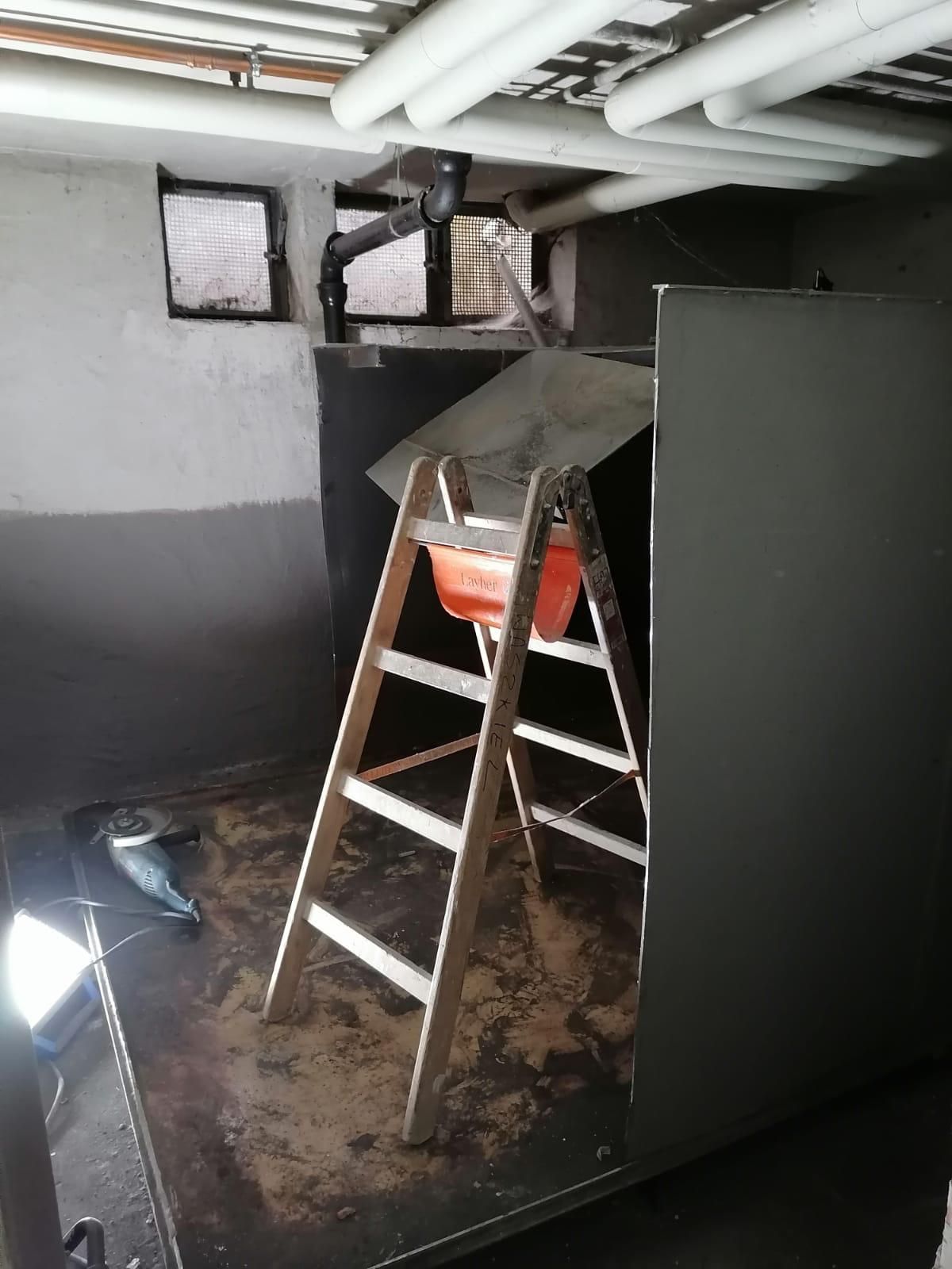 A wooden ladder is sitting in a room next to a wall.