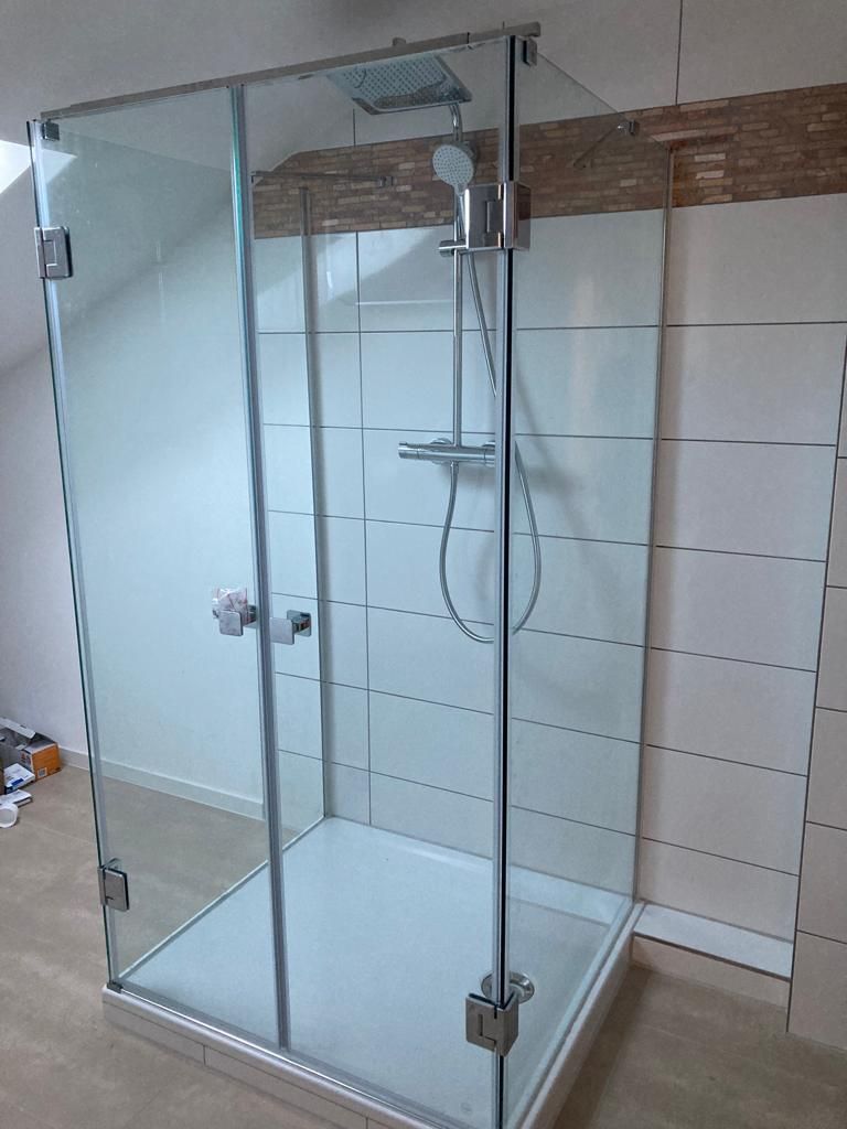 A shower stall with a glass door and a shower head in a bathroom.