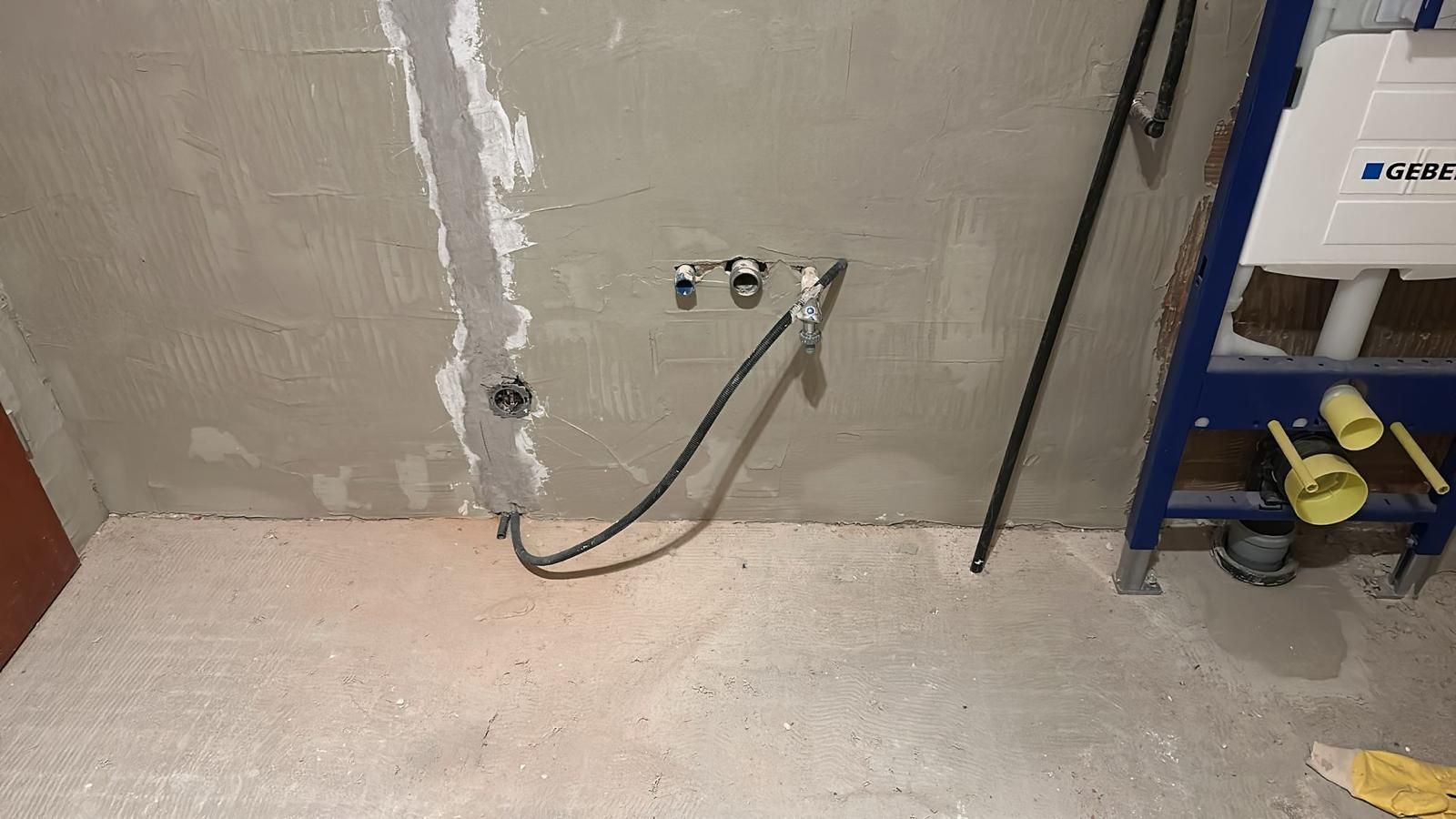 A bathroom under construction with a hose attached to the wall.