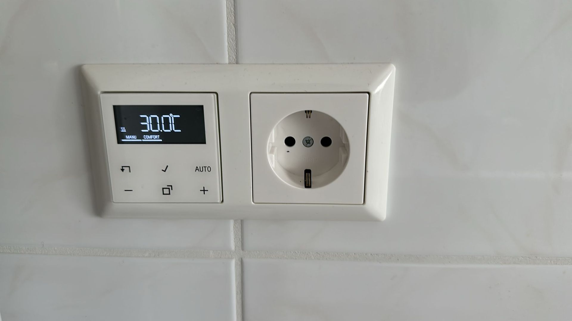 A thermostat is plugged into a socket on a wall.