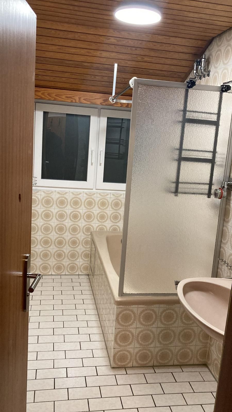 A bathroom with a bathtub , sink , shower and window.