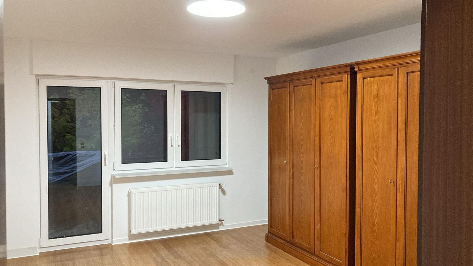 There is a window in the corner of the room with a sliding glass door.