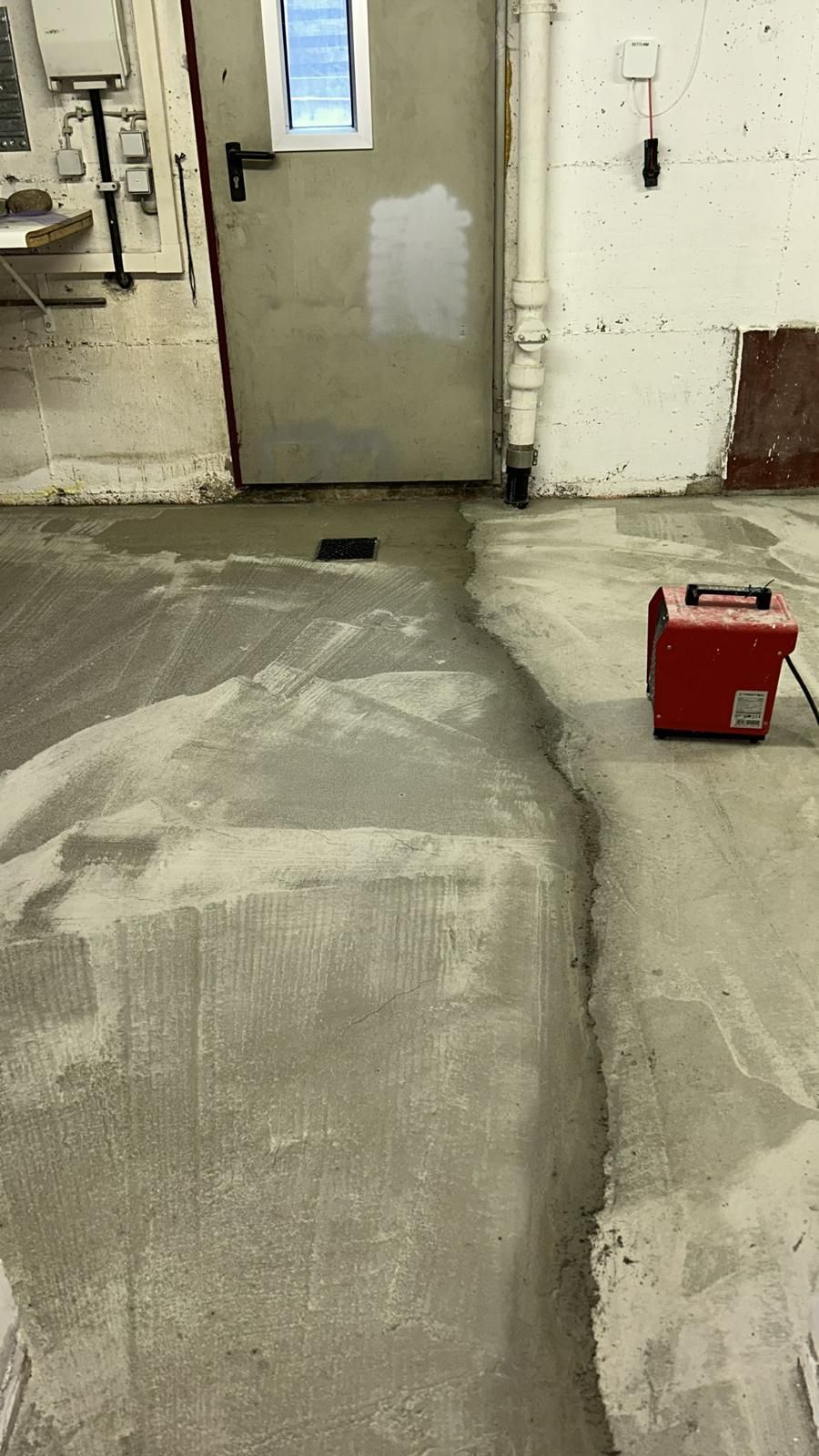 A red box is sitting on the floor in a room next to a door.