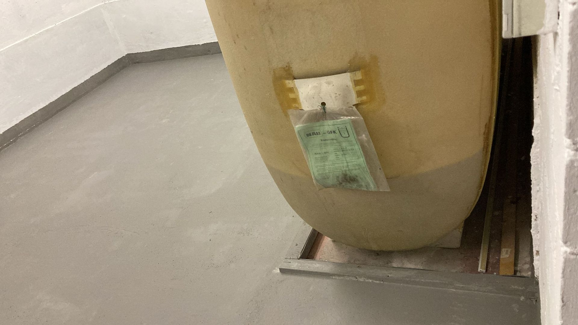 A large tank is sitting in a room next to a wall.