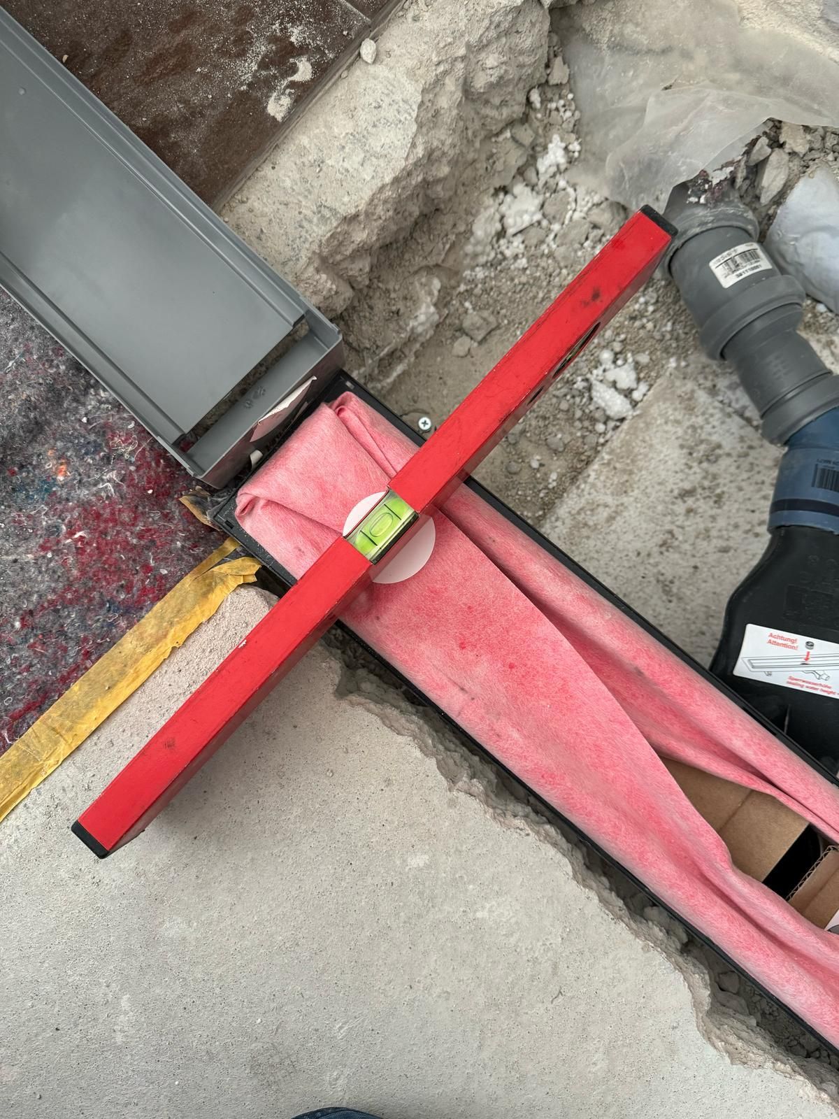 A person is using a red level to check the level of a pipe.