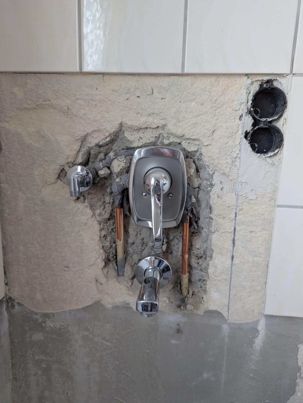 A bathroom faucet is being installed in a hole in the wall.
