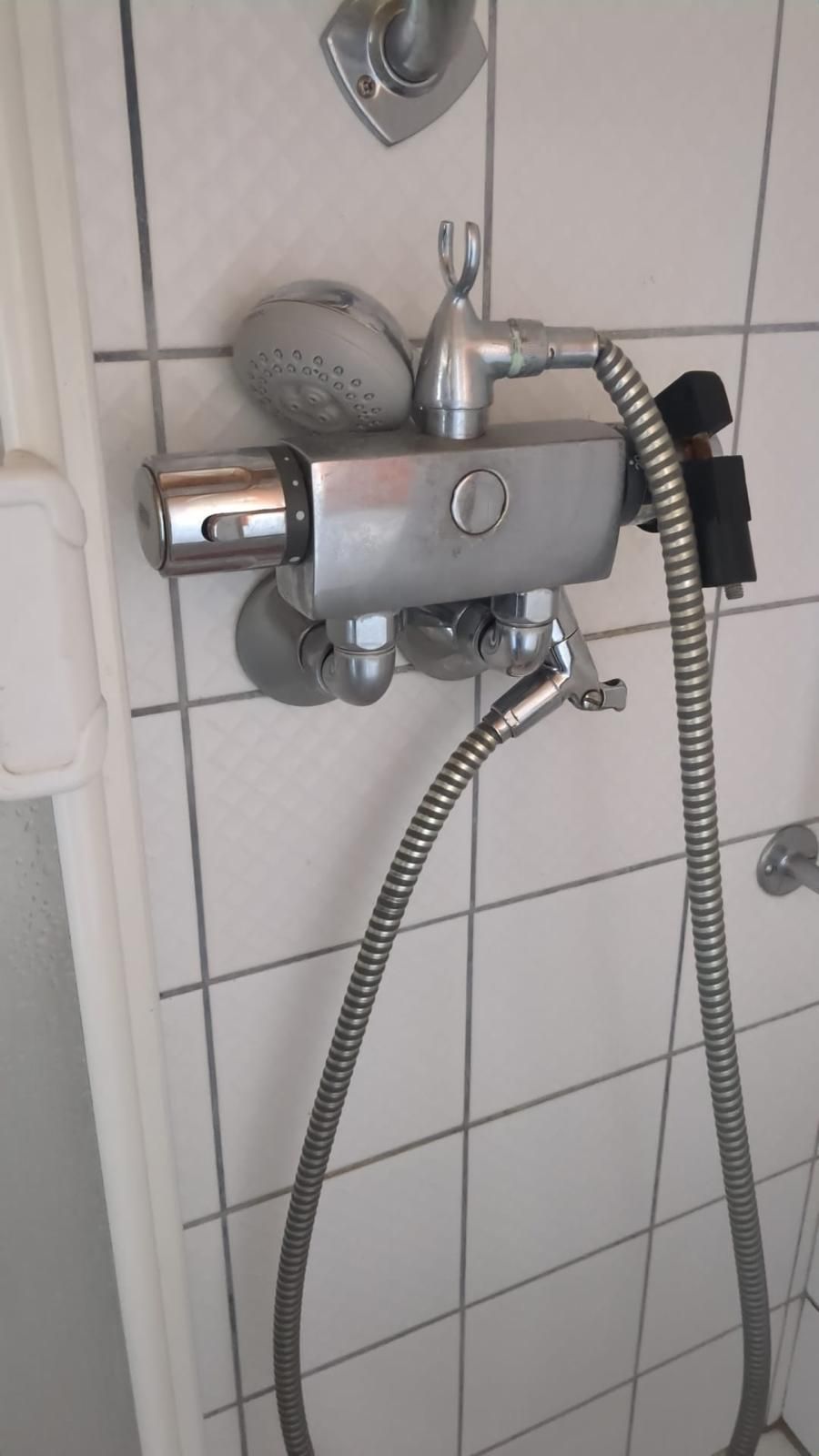 A shower head with a hose attached to it in a bathroom.