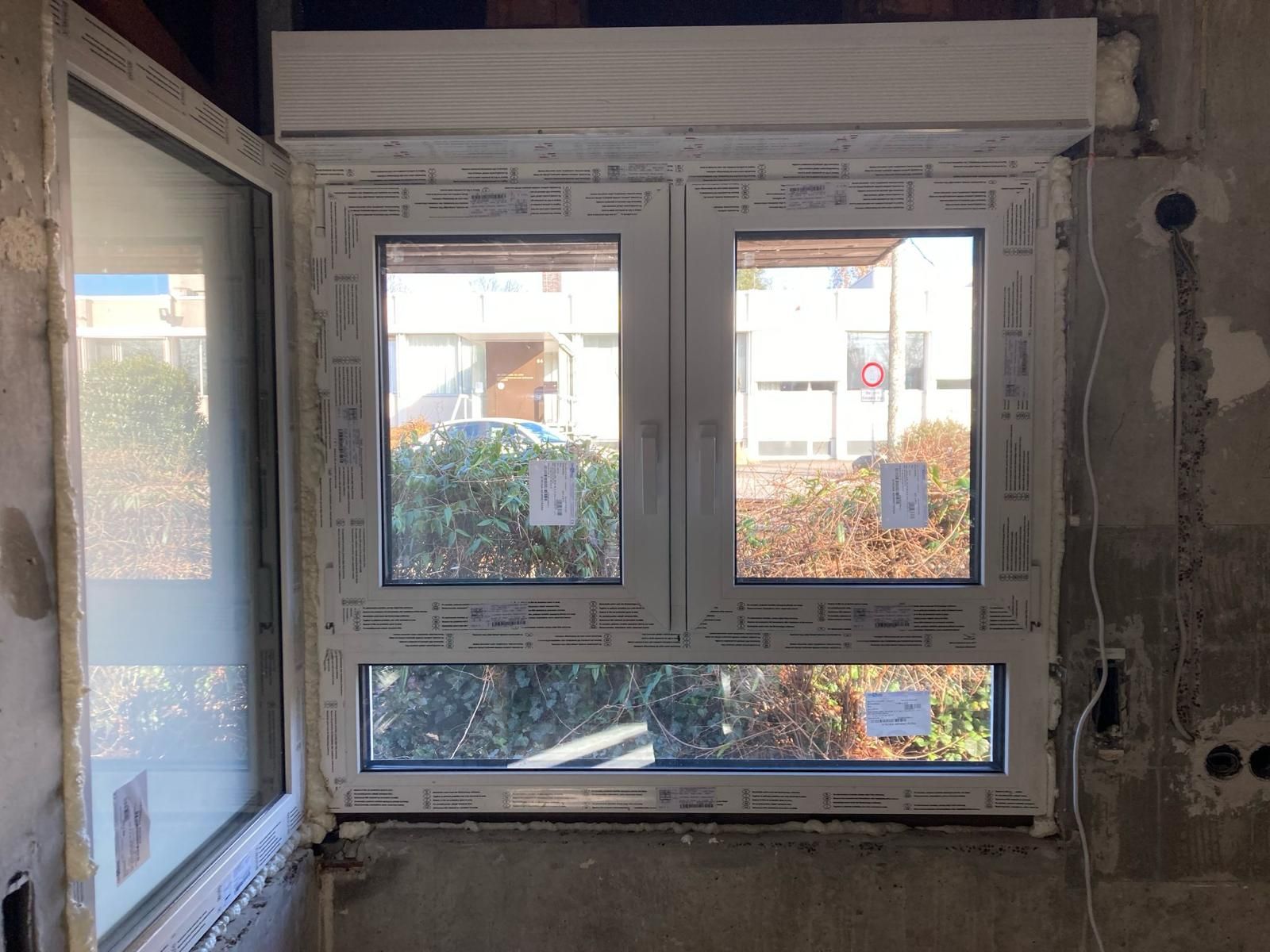 A window is being installed in a room with a gray wall.
