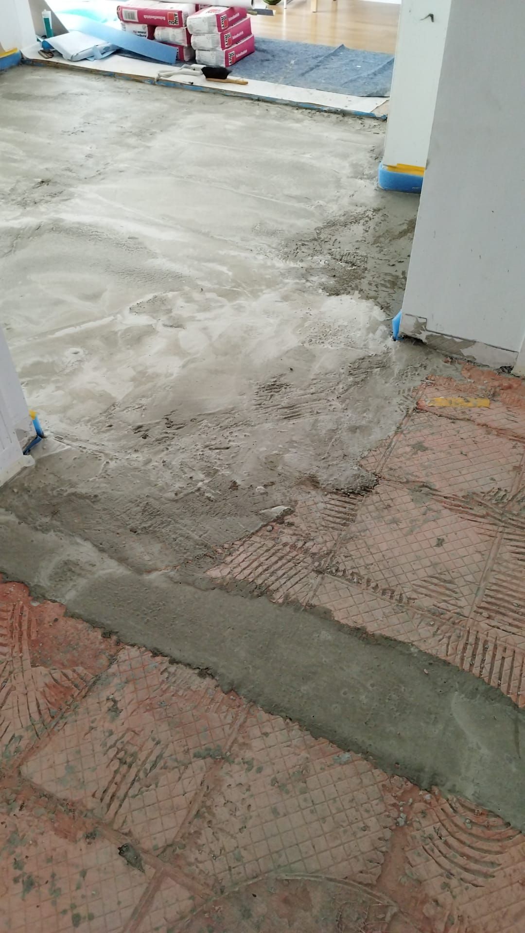 Construction site. Concrete floor with wet cement and partially covered with red brick.