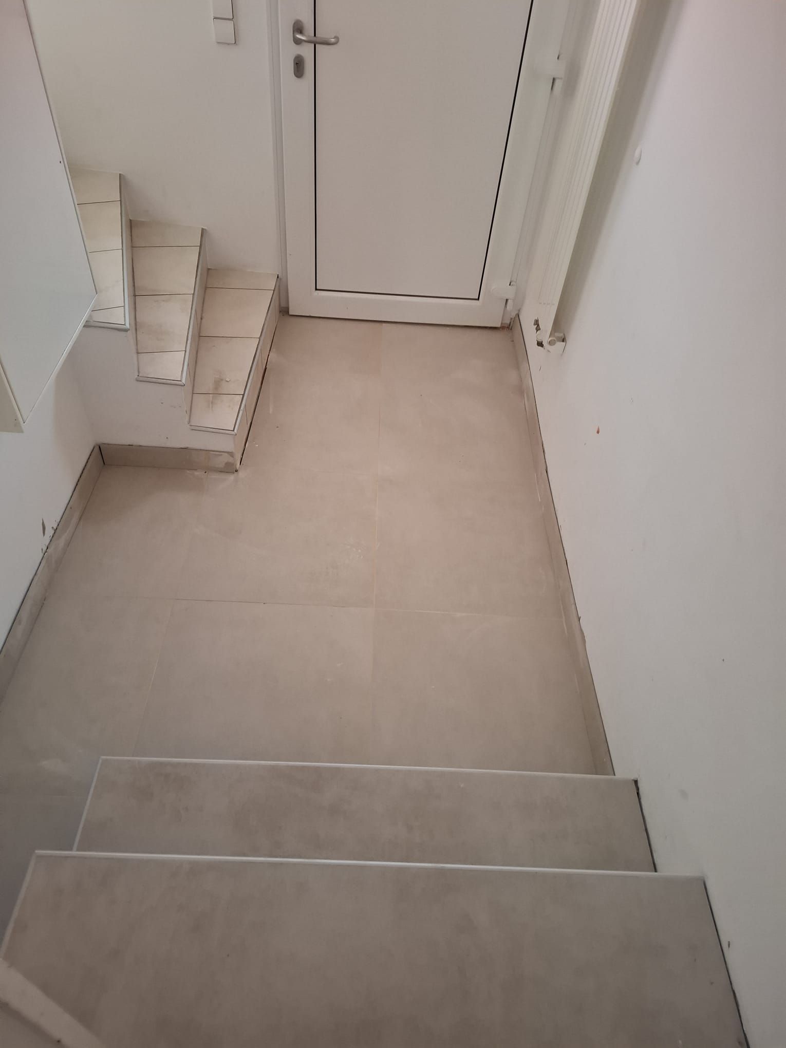 Staircase with tile steps and flooring, leading up to a white door.