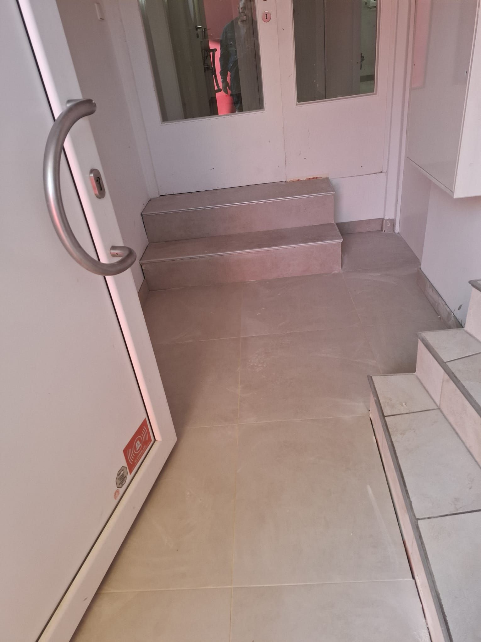 Interior doorway with steps leading up to an entrance area; white door with silver handle is open.