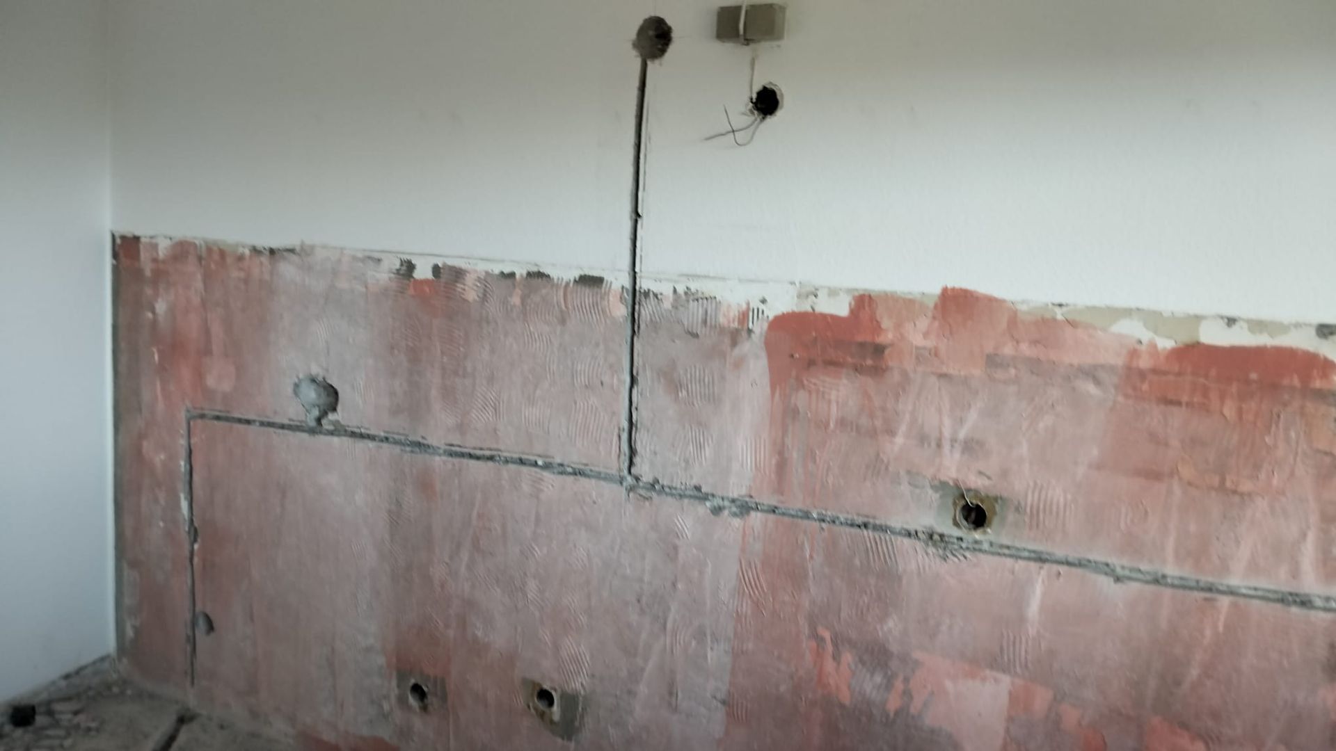 Electrical wiring in a wall, likely for a kitchen, with exposed conduit and outlets.