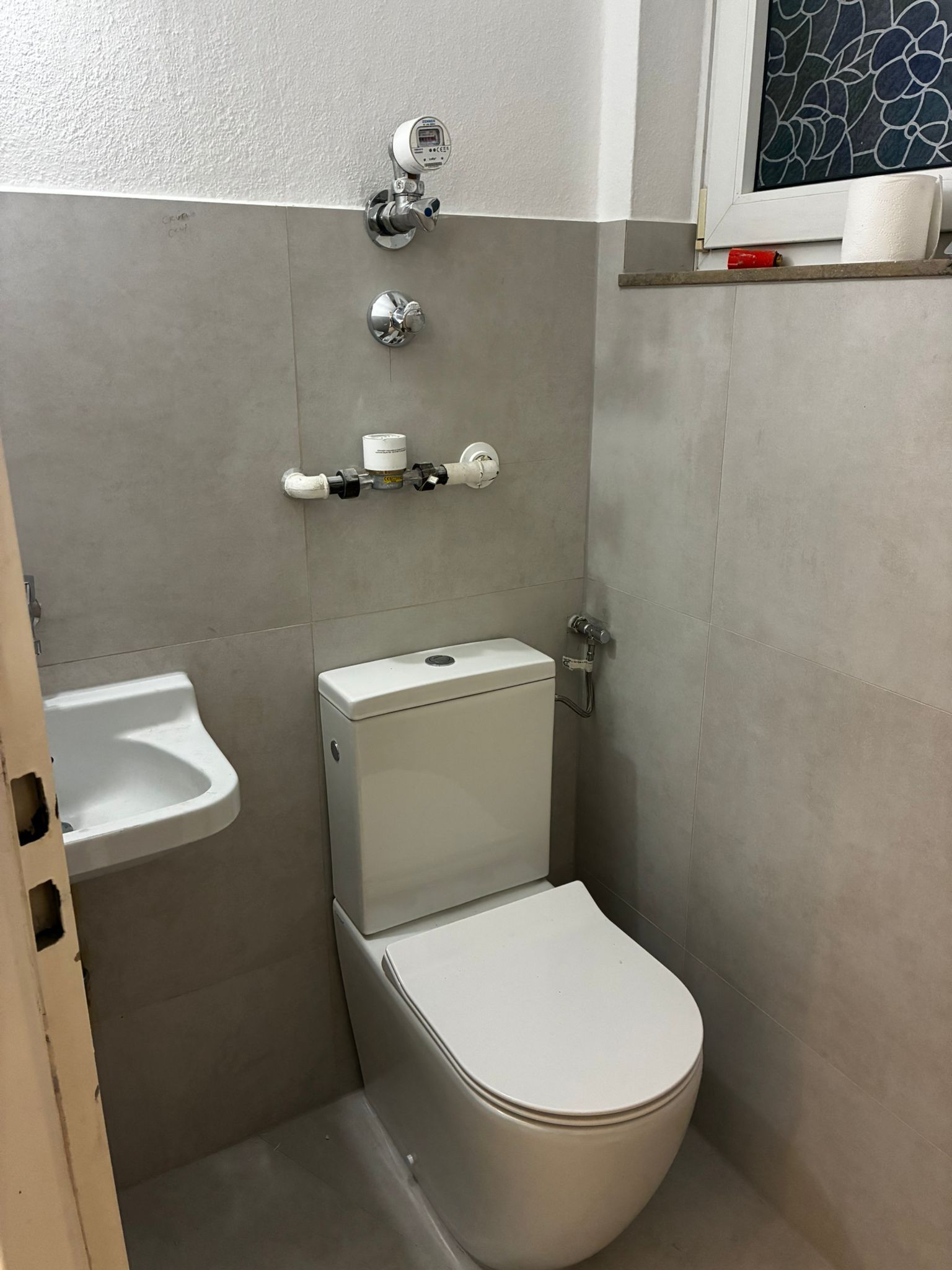 Small modern bathroom with gray walls, toilet, sink, and chrome fixtures.