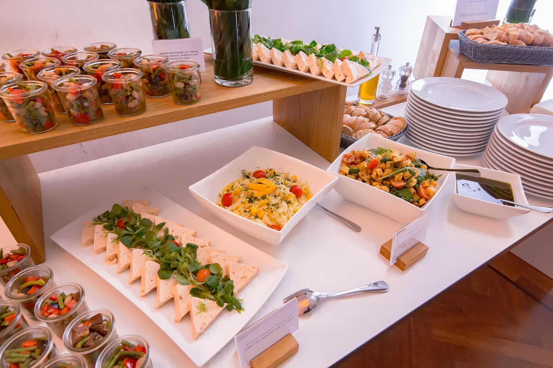 Ein Buffet mit verschiedenen Vorspeisen, darunter Gläser, weiße rechteckige Platten und Salatschüsseln.