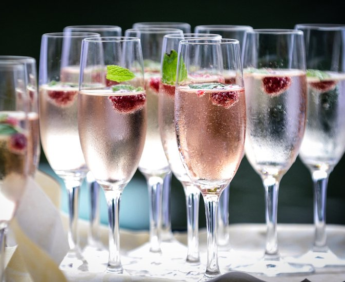 Hände stoßen mit farbenfrohen Cocktails an einem Restauranttisch an.