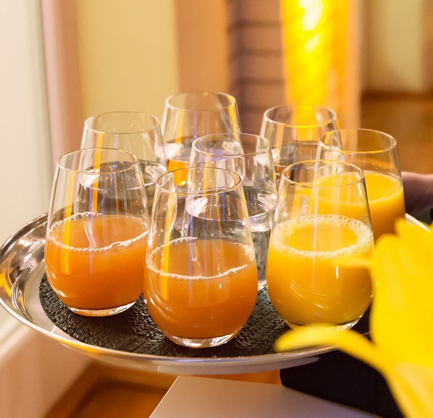 Menschen prosten sich zu. Hände halten Longdrinkgläser mit Cocktails und treffen sich mittig über einer Tischplatte