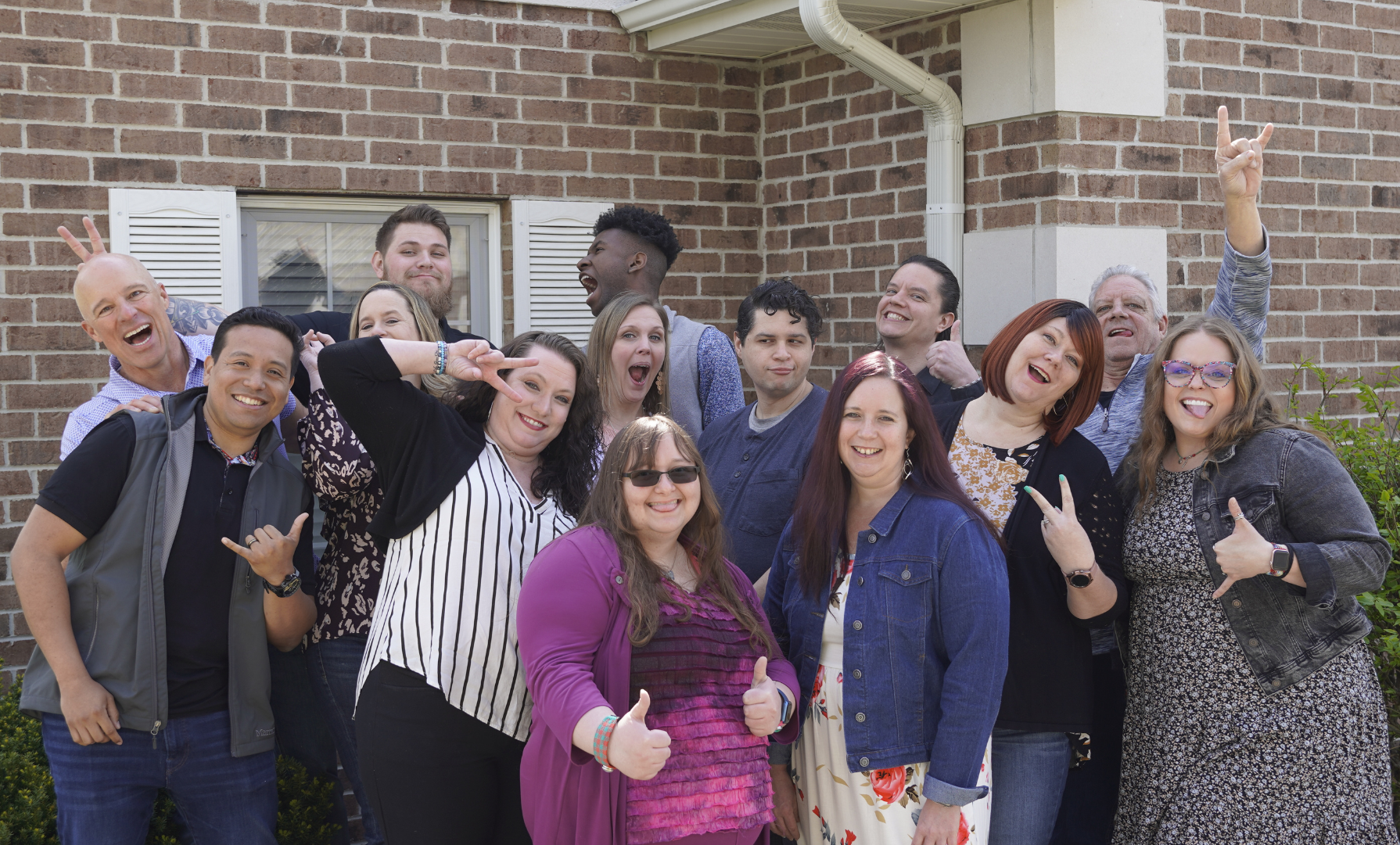 A group of people are posing for a picture in front of a brick building.