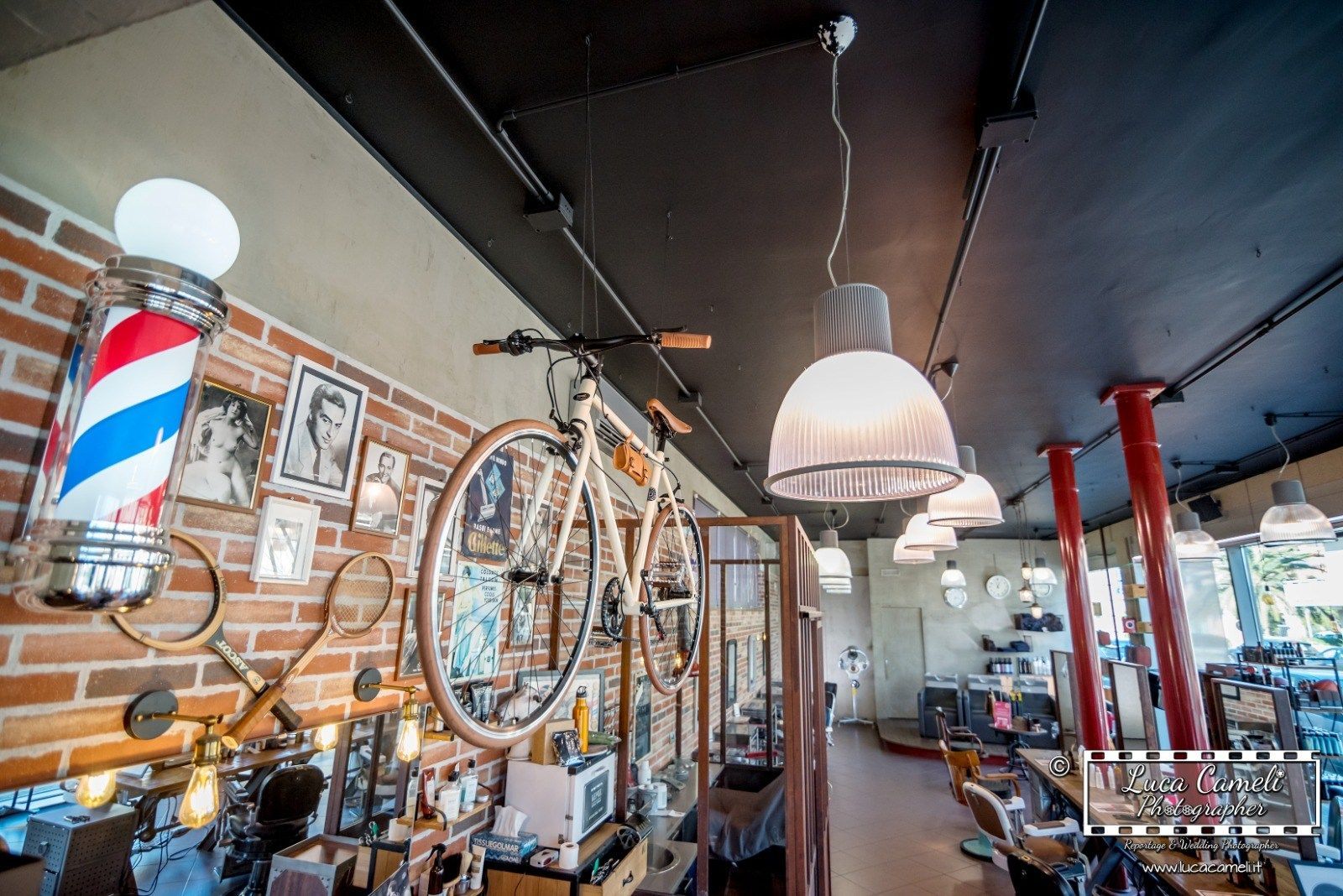 Interno di un barbiere con mattoni a vista, decorazioni a forma di bicicletta e palo da barbiere.