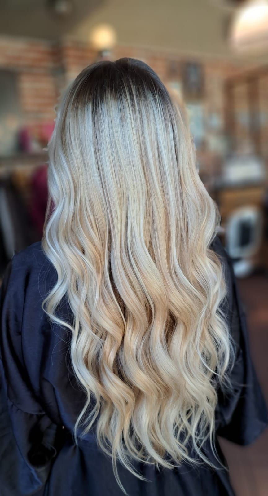 Donna con capelli biondi lunghi e ondulati; radici scure.