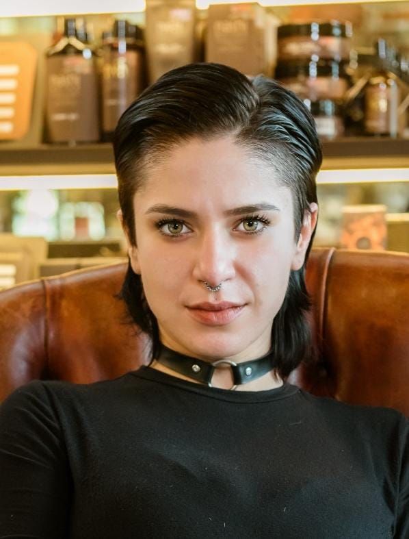 Donna con capelli corti e scuri, che indossa un girocollo nero, guarda direttamente la telecamera.
