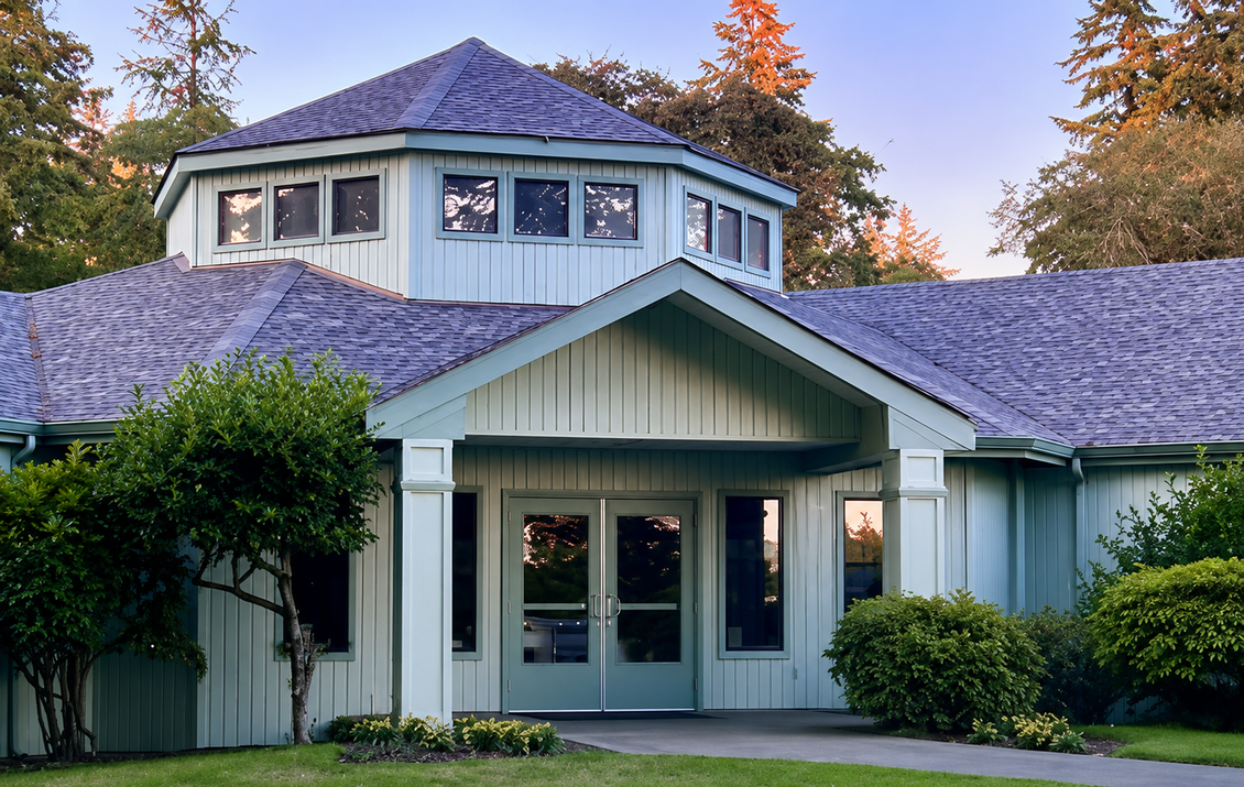 White house with teal trim and shingled roof, viewed from the front at dusk.