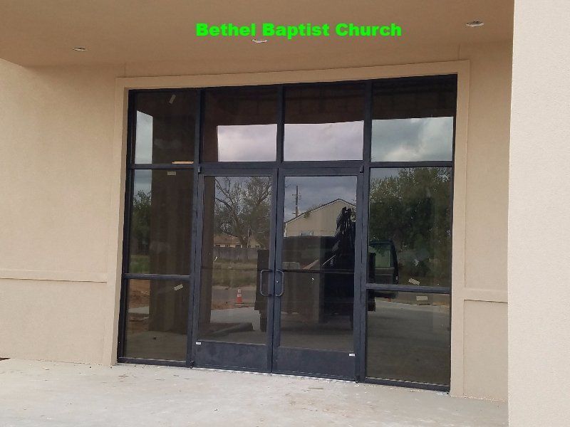 Glass entrance doors at Bethel Baptist Church under a beige overhang