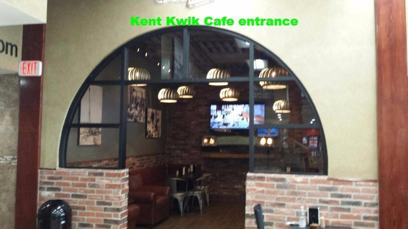 Entrance to Kent Kwik Café with arched window, brick half-wall, and seating inside