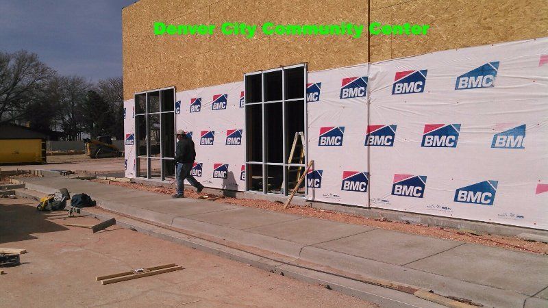Front entrance of a building under construction with BMC signs and green 