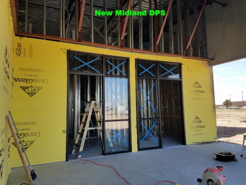 Yellow exterior wall with blue-framed doors and construction materials at a building site