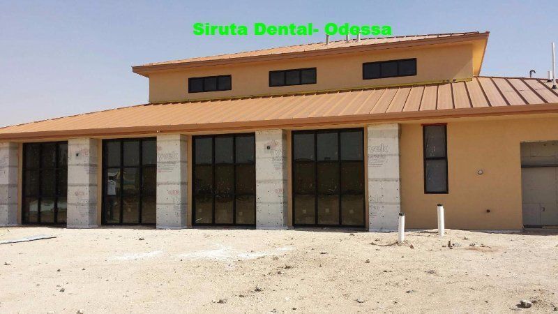 Small tan commercial building with green signage reading “Siruta Dental, Pasa” and glass storefront doors