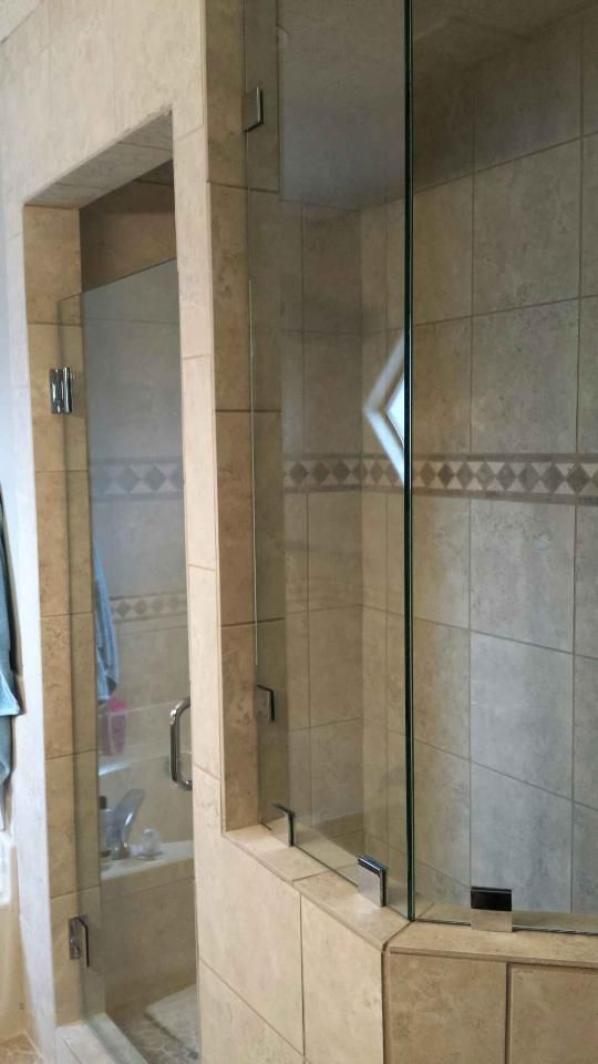 Tiled bathroom shower with glass enclosure and a built-in ledge