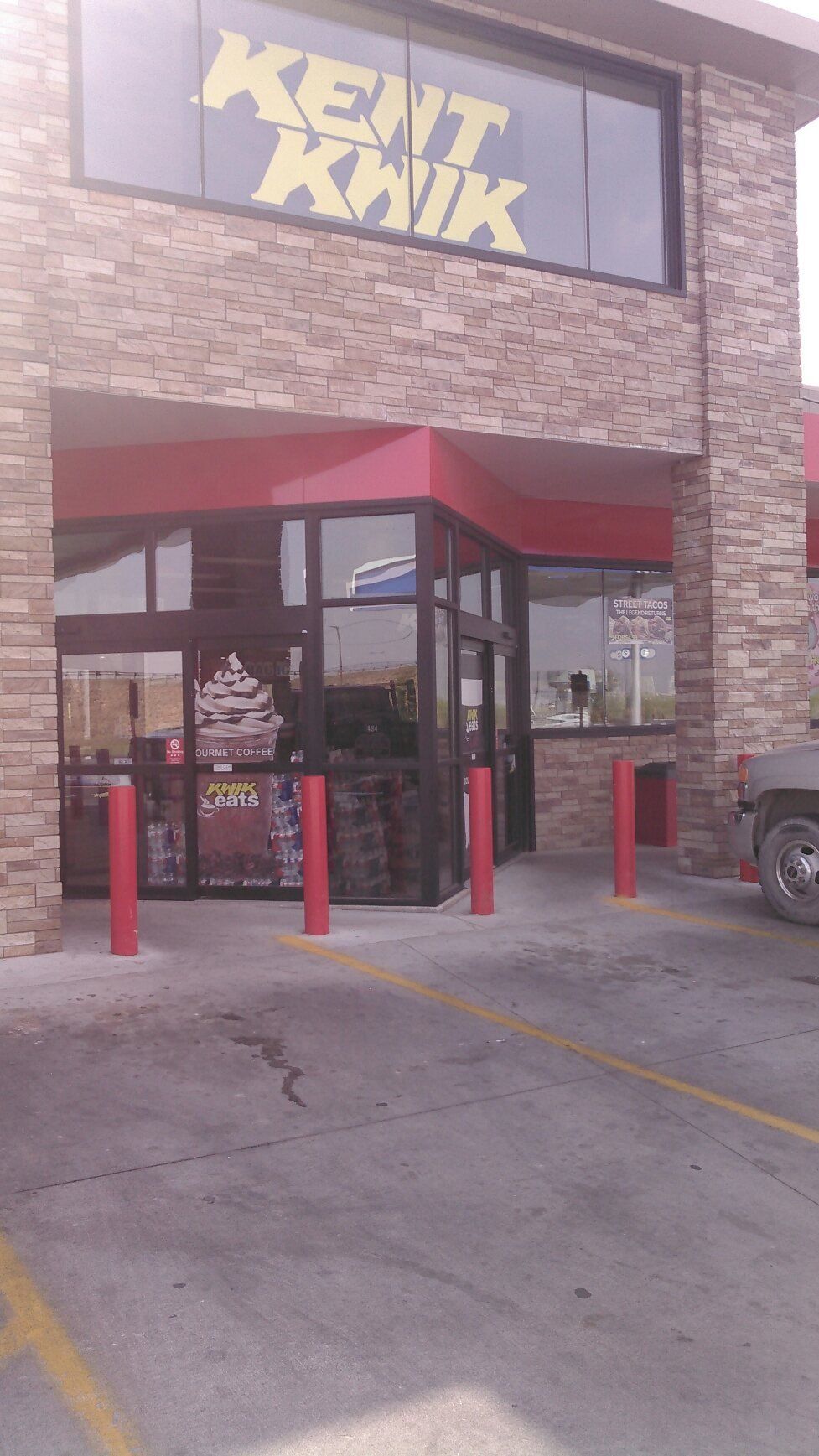 Storefront entrance with a red awning, stone facade, and “KENT KWIK” sign above the door.