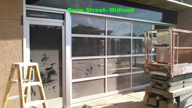 Storefront with glass doors and windows, step ladder on the left, stacked construction materials on the right.