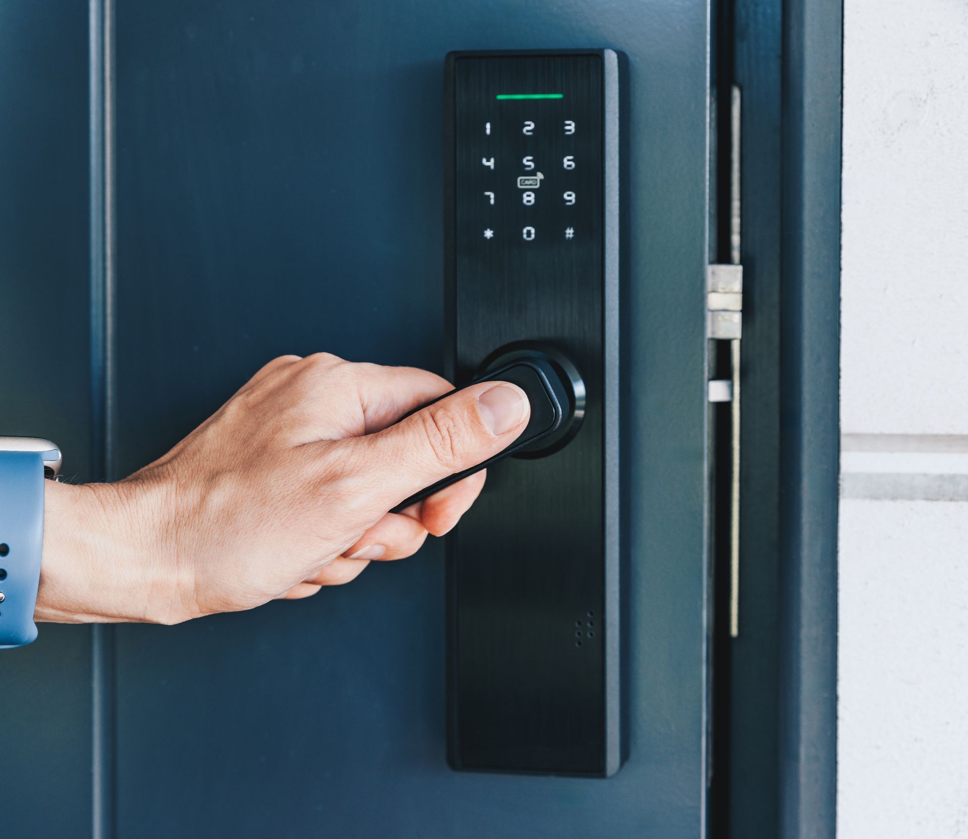 Hand turning a keypad lock on a dark blue door