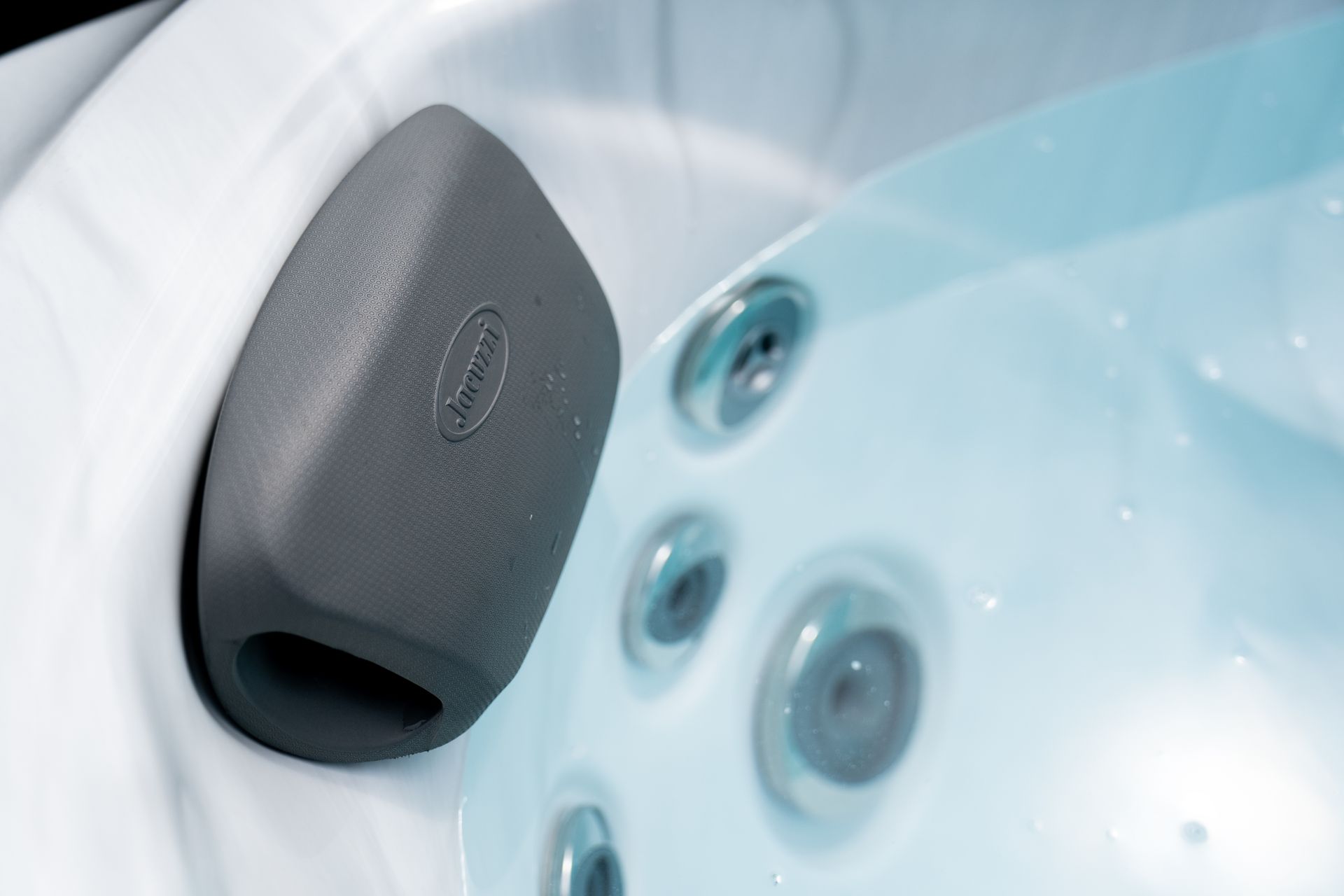 Gray spa headrest beside blue bathtub jets and controls