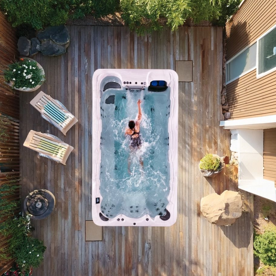 Overhead view of a person swimming in a small backyard pool on a wooden deck