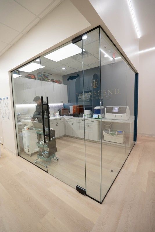 Dental office reception area with blue wall logo, white cabinets, and countertop equipment - Transcend Dental Office Photo