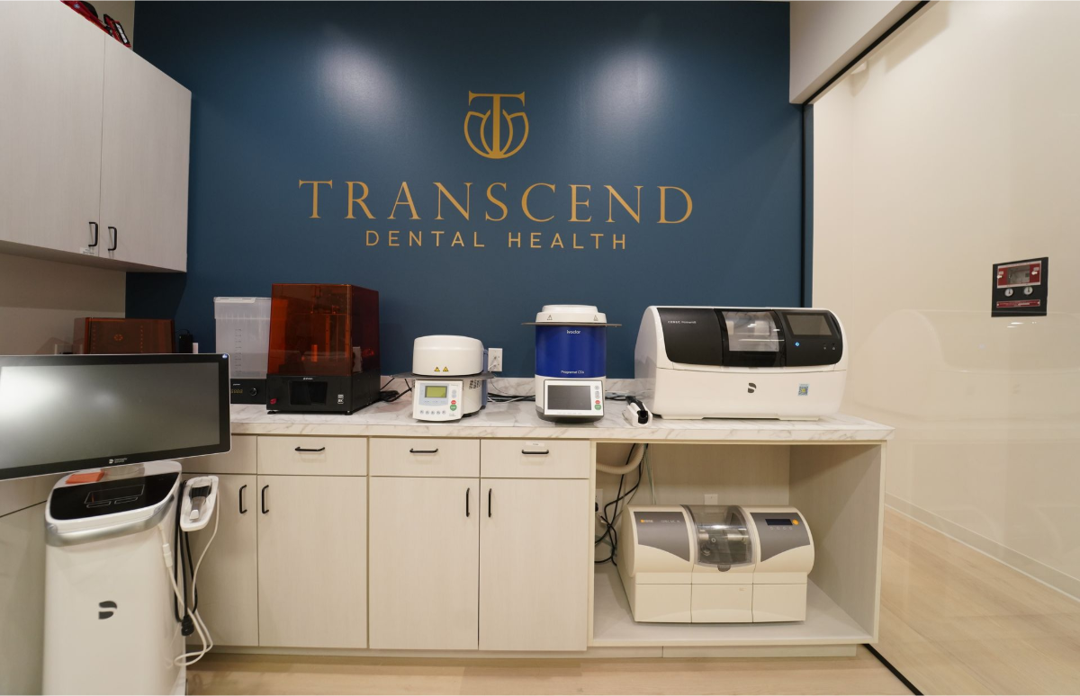 Dental office reception area with blue wall logo, white cabinets, and countertop equipment - Transcend Dental Office Photo