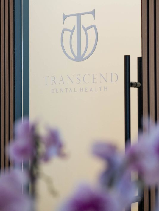 Hallway with frosted glass logo and text reading “TRANSCEND DENTAL HEALTH” at the end. - Transcend Dental Office Photo